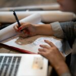 person in white shirt writing on white paper