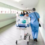 person walking on hallway in blue scrub suit near incubator