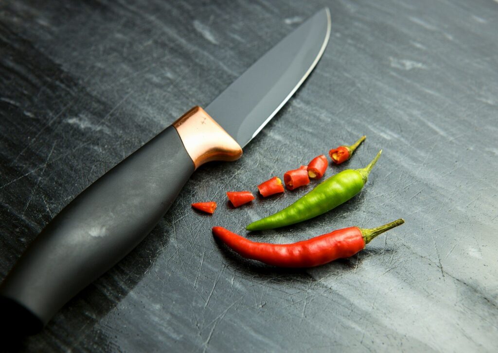 a knife and some red and green peppers