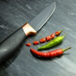 a knife and some red and green peppers
