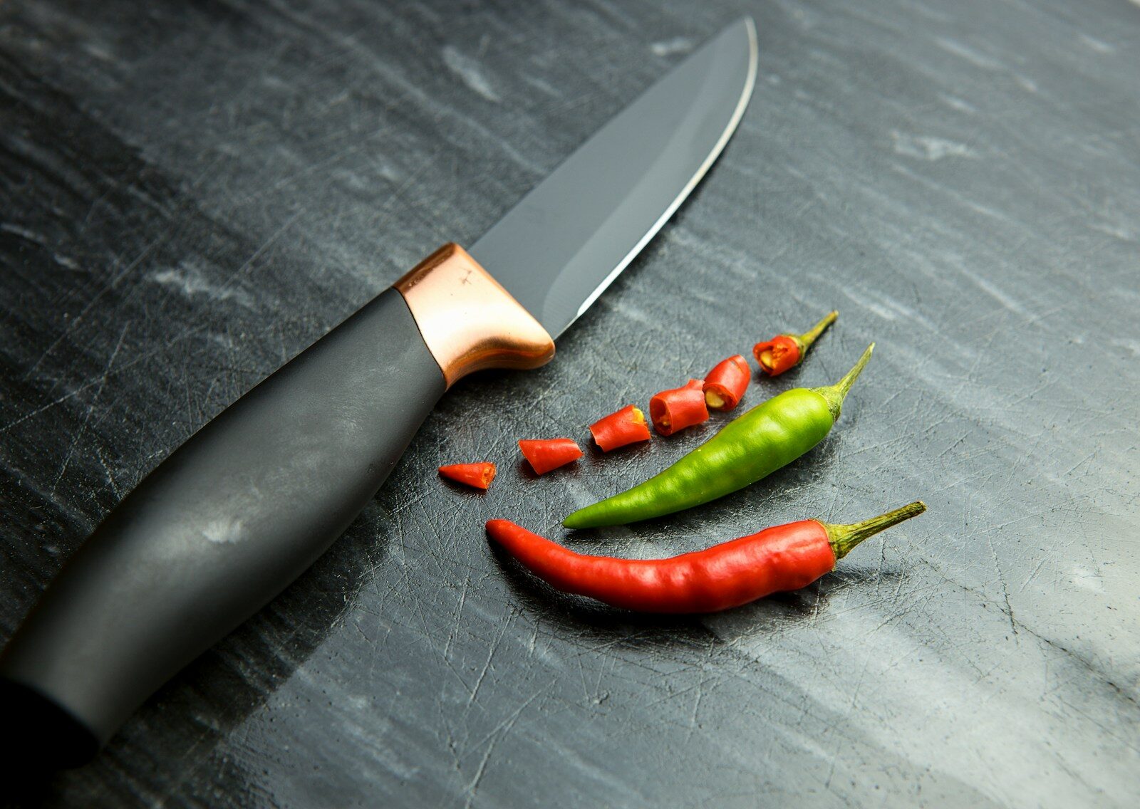 a knife and some red and green peppers
