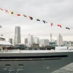 A large yacht sails with city skyline in the background