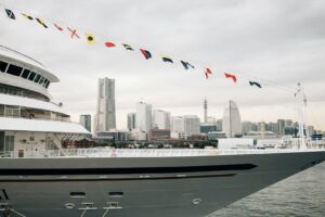 A large yacht sails with city skyline in the background